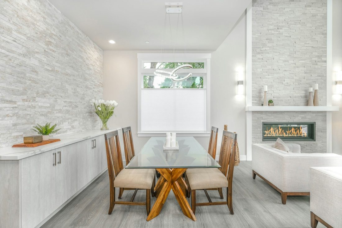 Bright modern dining room with a light textured stone accent wall and a glass-topped table