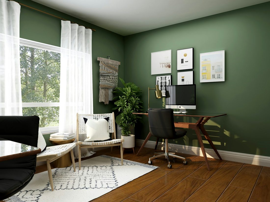 Home office with a calm sage-green accent wall, a wooden desk and framed prints