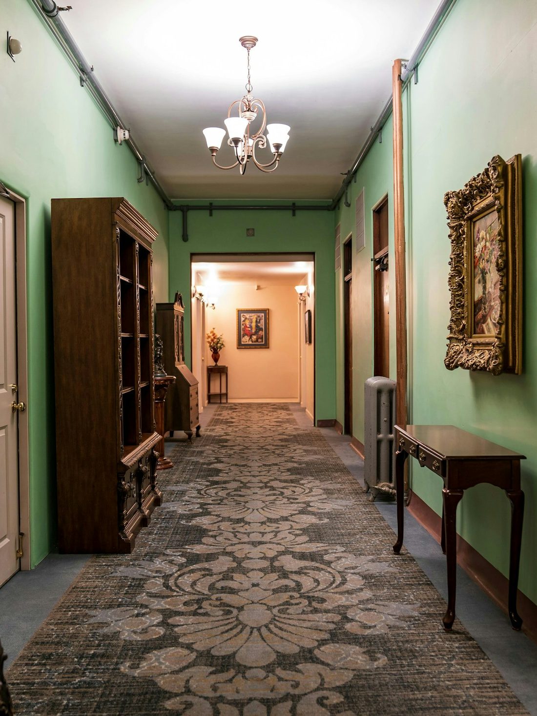 Characterful hallway with soft green walls, a patterned runner and a pendant light