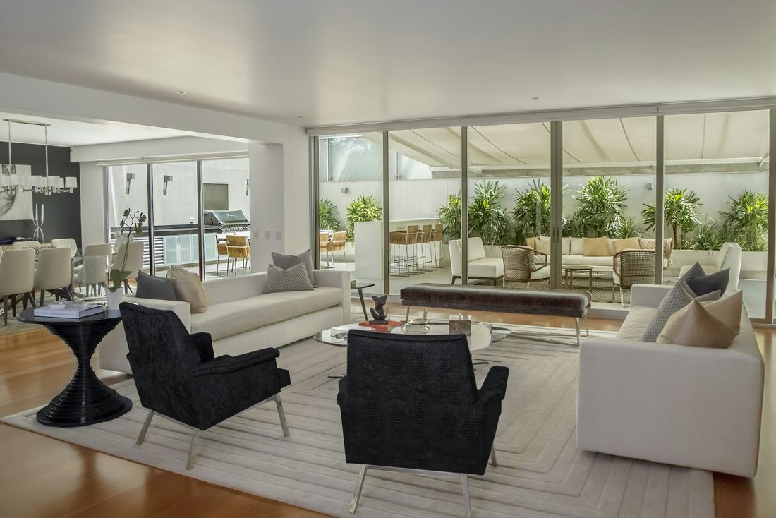 Open-plan living room with clean gallery-white walls, dark armchairs and floor-to-ceiling windows