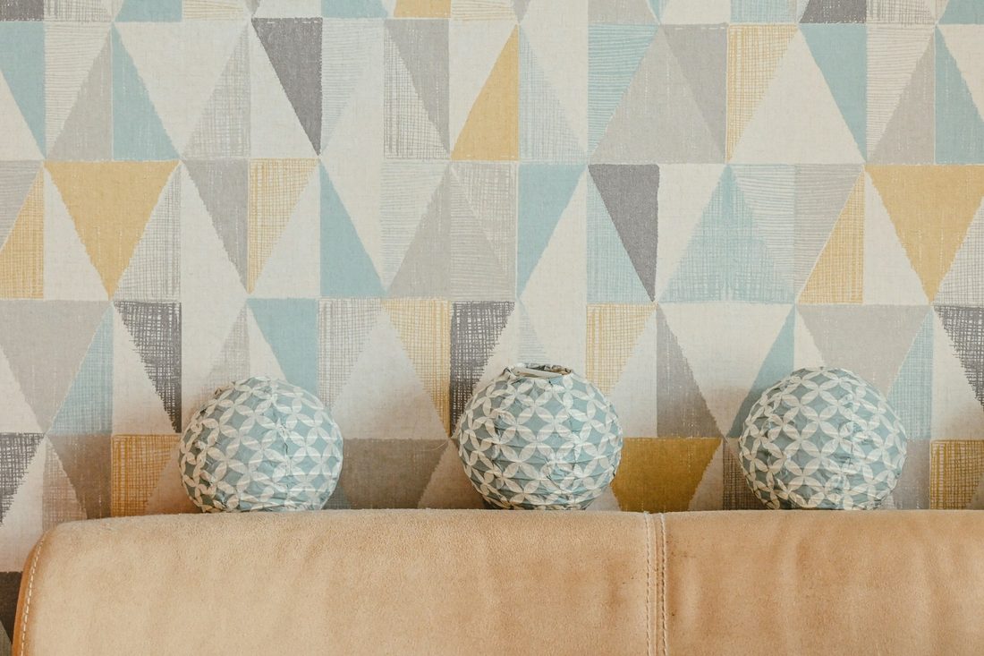 Close pattern detail of a soft geometric wallpaper in pastel tones behind a sofa